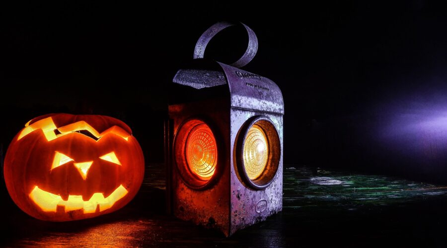 Calabaza de Halloween tallada y farol antiguo iluminados sobre madera oscura