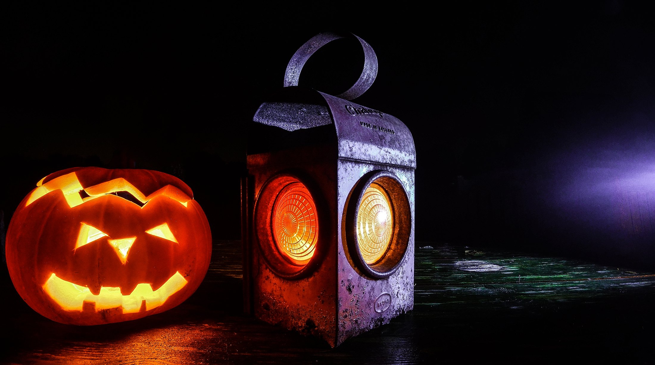 Calabaza de Halloween tallada y farol antiguo iluminados sobre madera oscura
